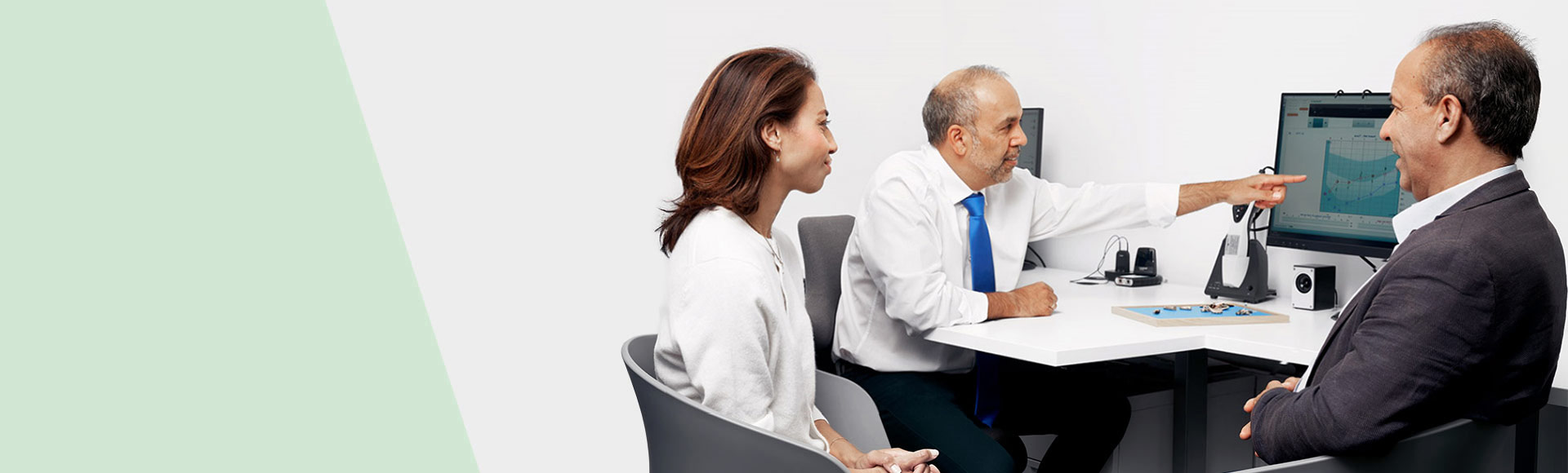 Audiologist explaining hearing test results to a customer using a computer screen.