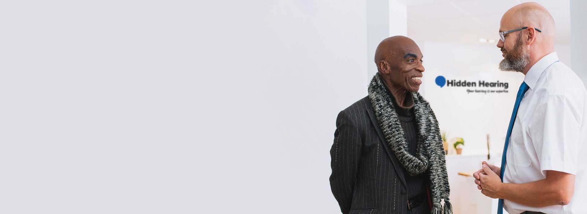 Audiologist discussing hearing care solutions with a customer at a Hidden Hearing clinic.