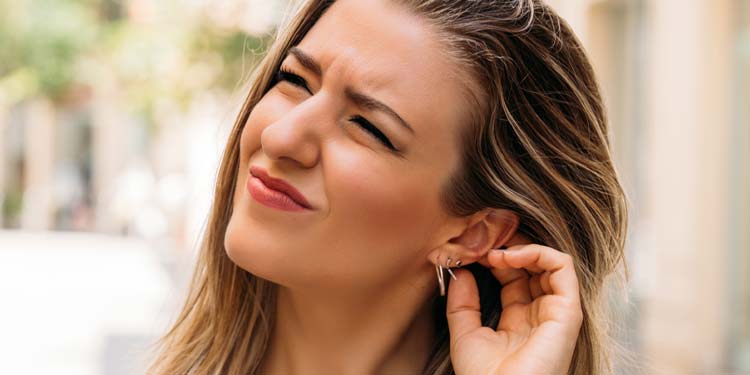 Image shows a woman finding a sound painful to hear