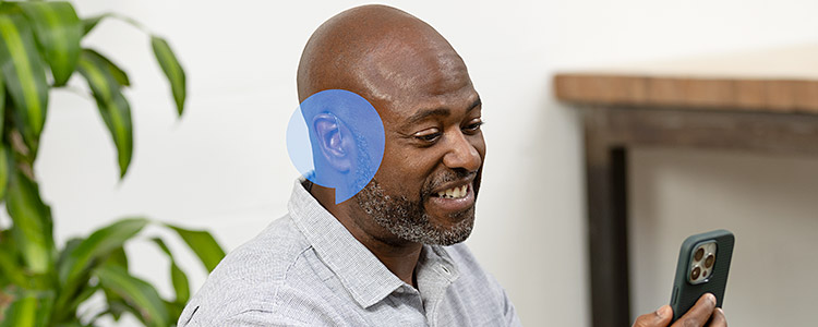 A man holding a smartphone with a blue soundwave graphic by his ear.