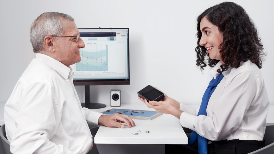 Hearing care professional demonstrates hearing aids to a customer during a consultation.