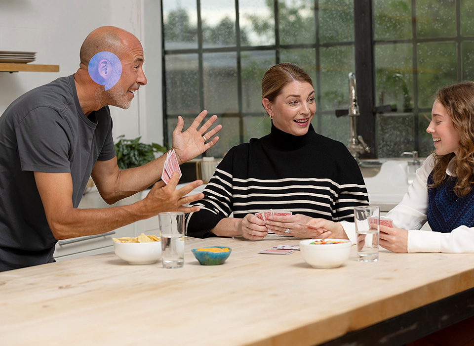Family playing cards together around a wooden table in a bright kitchen.