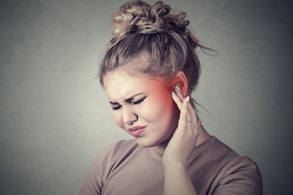 Woman touching her ear in discomfort