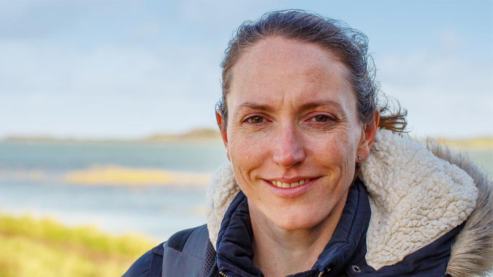 Hidden Hearing customer Helen enjoying a peaceful outdoor setting near a lake.