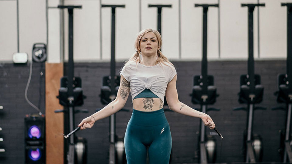Hidden Hearing customer Katie Lee jumping rope in a gym setting