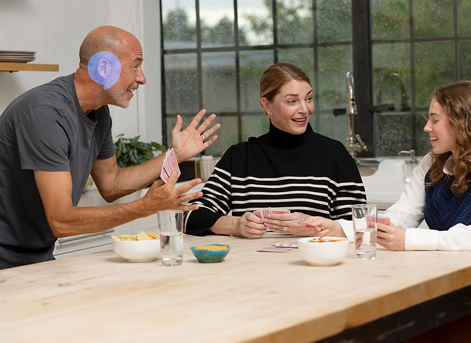 Family playing cards together around a wooden table in a bright kitchen.