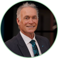 Dr Hilary, hearing care specialist, wearing a navy suit and teal-patterned tie.