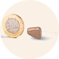 Comparison of the Oticon Own hearing aid’s size next to a pound coin