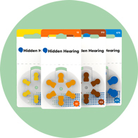Hidden Hearing branded hearing aid batteries in yellow, orange, brown, and blue packaging.