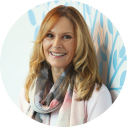 Hearing aid user Sandra Pierce standing in front of a patterned wall.
