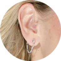Silver Figaro chain hearing aid accessory from DeafMetal worn on the ear.