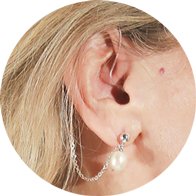 Hearing aid accessory with a silver chain and pearl stud earring designed for style and practicality.