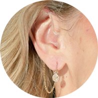 Hearing aid adorned with a DeafMetal Cat’s Eye jewelry attachment featuring a stylish chain and gemstone accent.