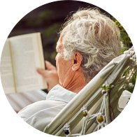 Man reading a book in a garden hammock while wearing a digital hearing aid