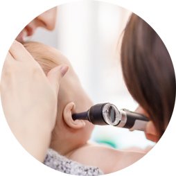 Healthcare professional examining a baby’s ear with an otoscope.