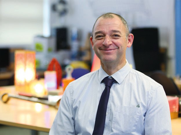 Hidden Hearing customer Alex Slight in a professional setting with blurred background.