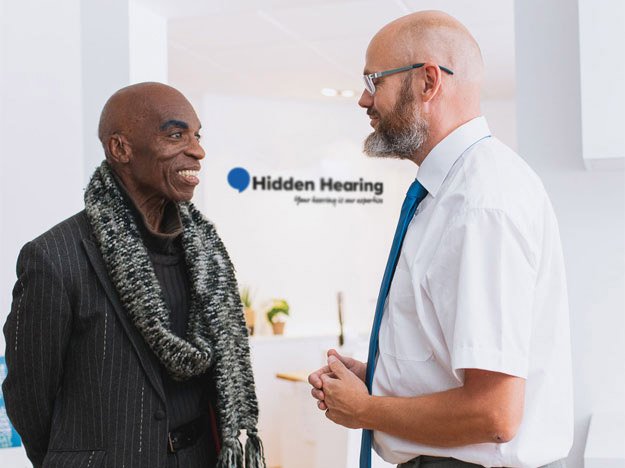 Hearing care specialist assisting a customer at a Hidden Hearing clinic.