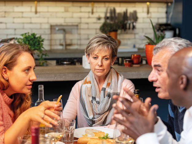 Woman experiencing hearing difficulty during a lively family dinner conversation.
