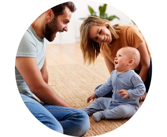 Family engaging with a baby on the floor, emphasizing early childhood hearing care.