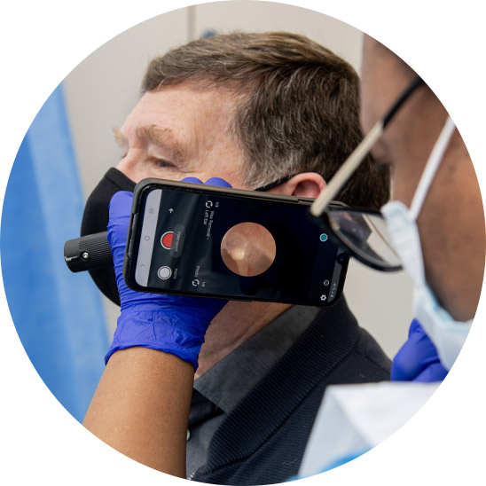 Hearing care professional using a specialized device to examine and remove earwax from a patient's ear.