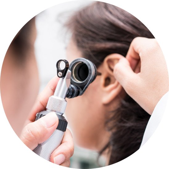 Audiologist examining a patient’s ear with an otoscope.