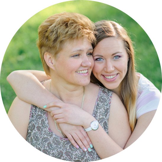 Mother and daughter embracing outdoors on a sunny day.