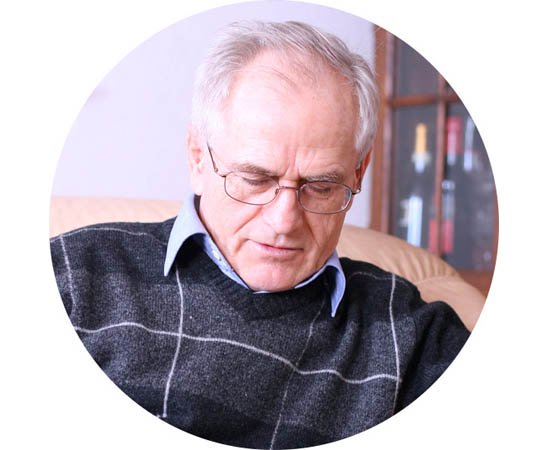 Elderly man resting in a comfortable armchair with a relaxed posture.