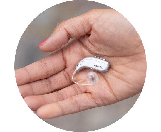 Oticon More hearing aid resting on an open palm