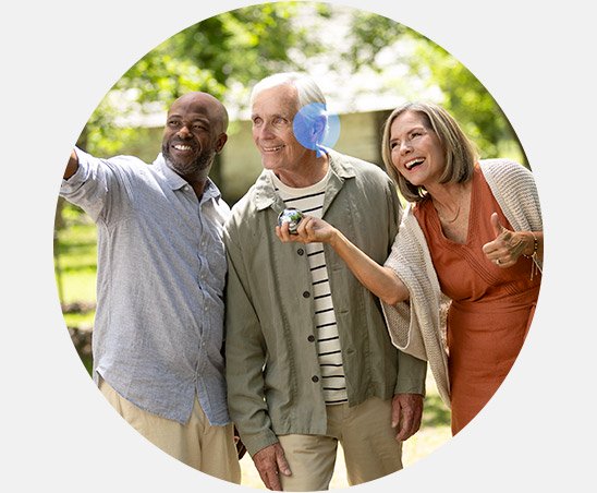Group of adults outdoors examining and discussing a modern hearing aid device.