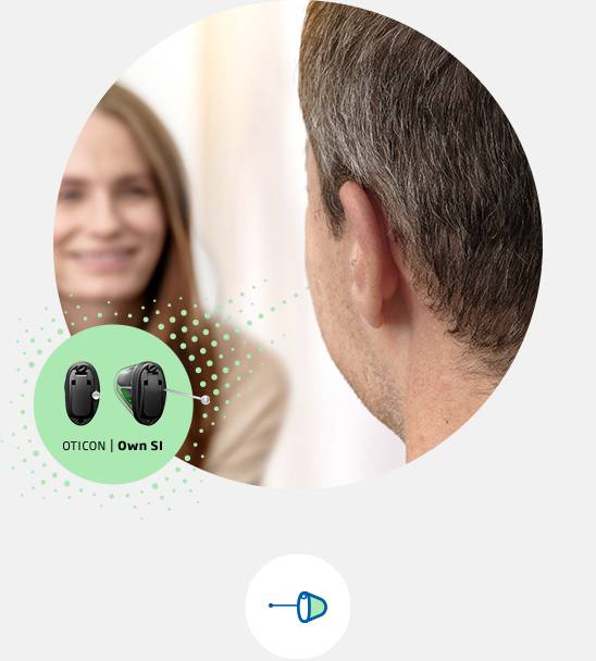 Oticon Own hearing aid placed discreetly in the ear of a man during a conversation.