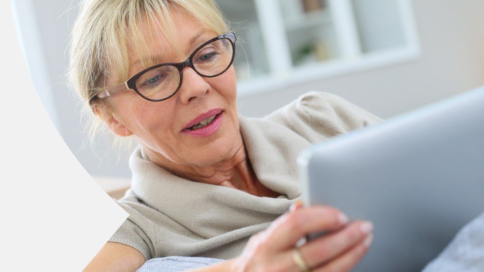 afbeelding van glimlachende vrouw die naar een tablet kijkt