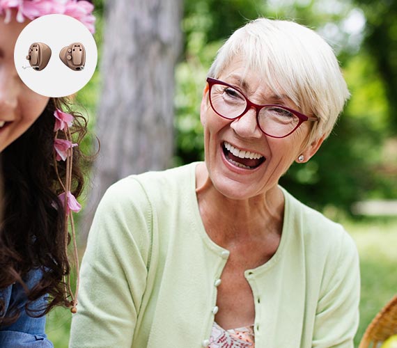 Uomo che indossa l'apparecchio acustico Audika Opn mentre interagisce all'aperto.