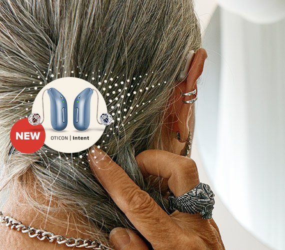 A close-up shows a person with silver hair adjusting their discreet Oticon hearing aid. A circular overlay highlights 'NEW Oticon | Intent' devices, emphasizing advanced technology for hearing care solutions.