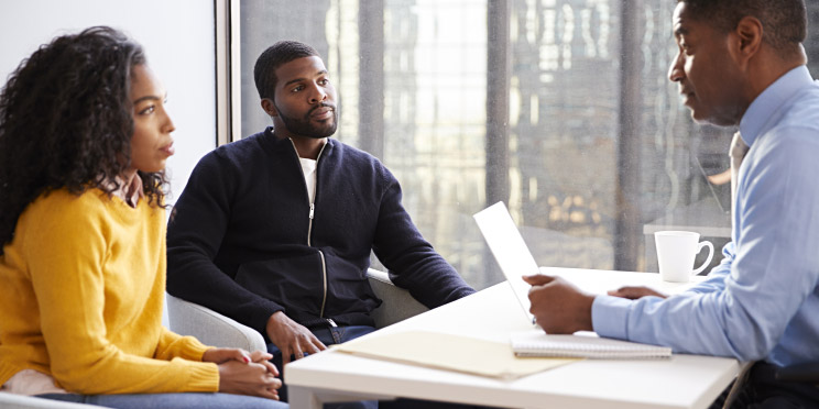 Image shows 3 people talking at a table