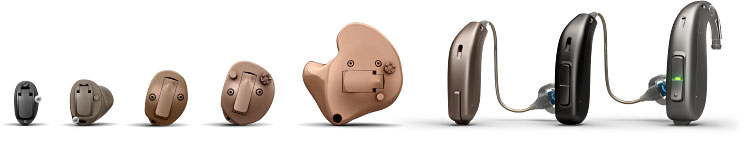 Various styles and types of hearing aids arranged in a row, including in-the-ear and behind-the-ear models.