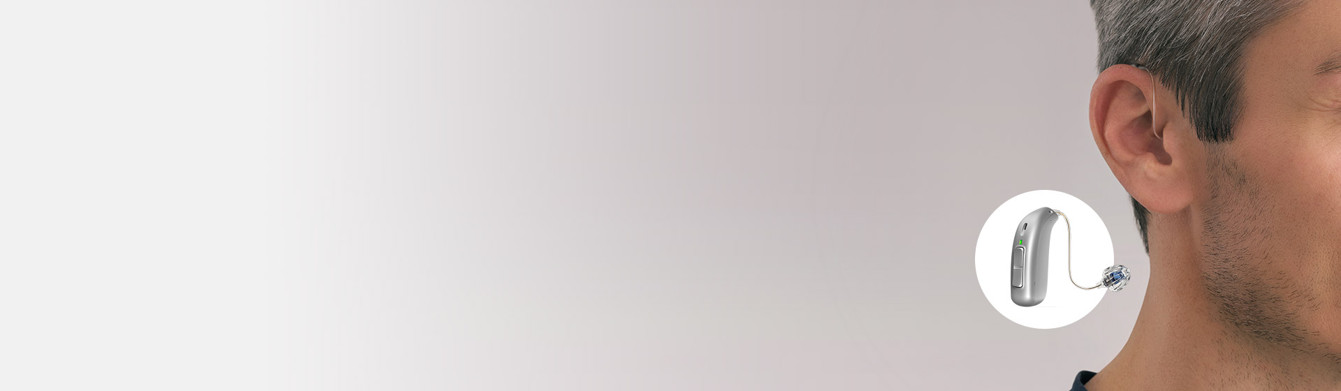 Hearing aid positioned behind the ear of a middle-aged man with a close-up of the device displayed.