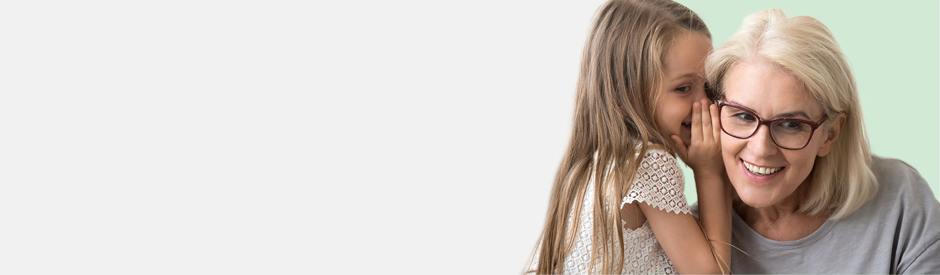 Young girl whispering into an older woman's ear.