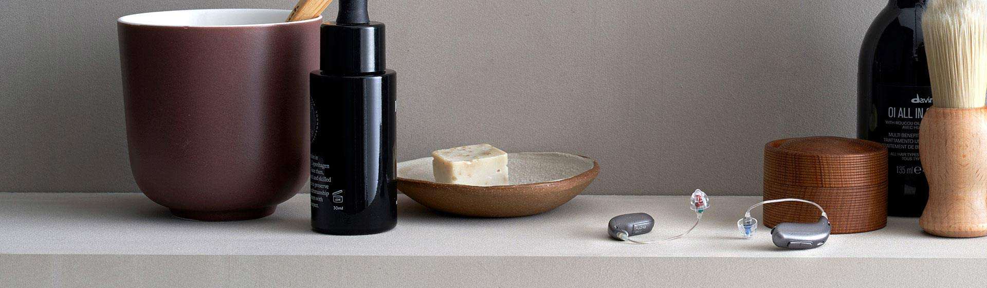 Audífonos digitales junto a productos de cuidado personal sobre una superficie.