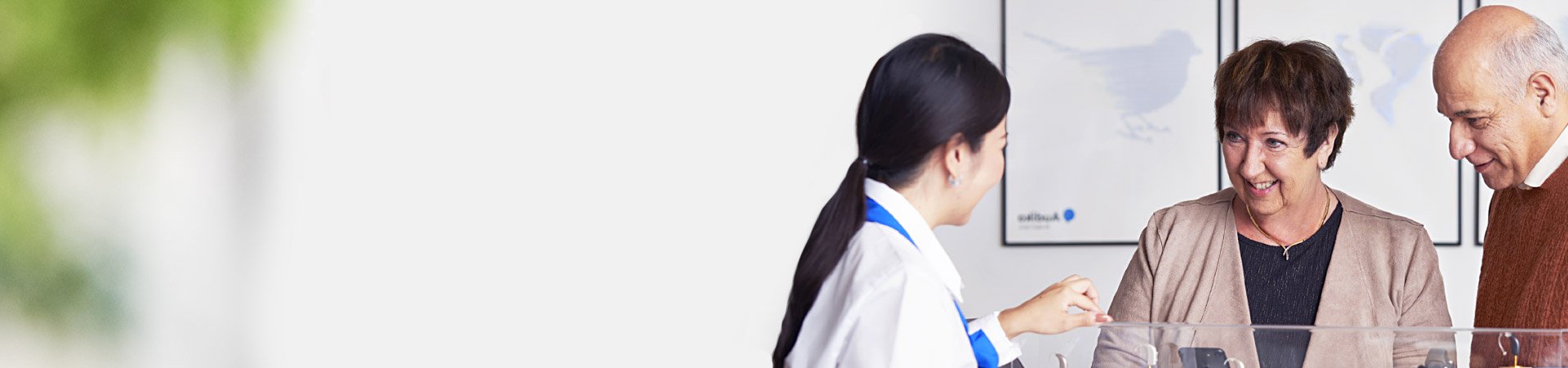 audiologist showing hearing aid to people smiling