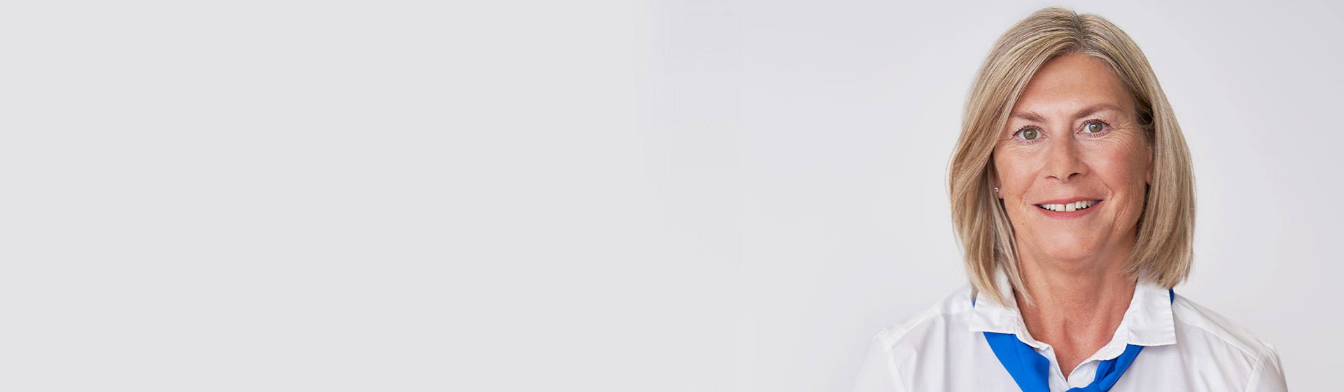 Kvindelig Audika-hørespecialist med hvid skjorte og blåt tørklæde.