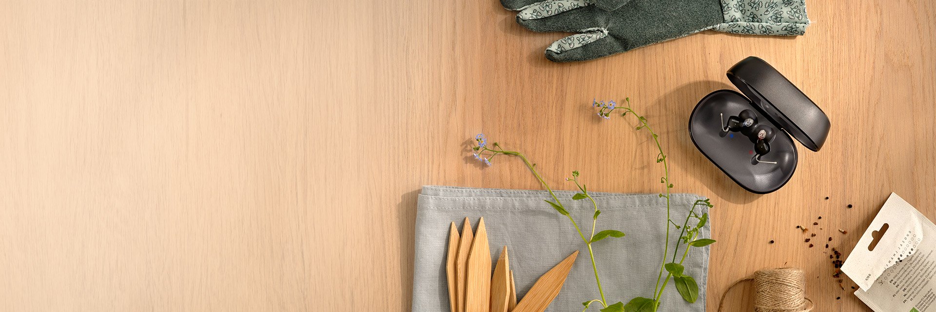 Das Oticon Zeal Hörgerät in der Ladeschale auf einem Holztisch, von oben fotografiert.