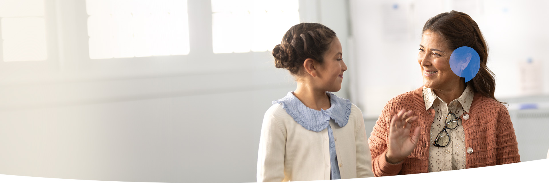 Image shows little girl whispering to woman's ear