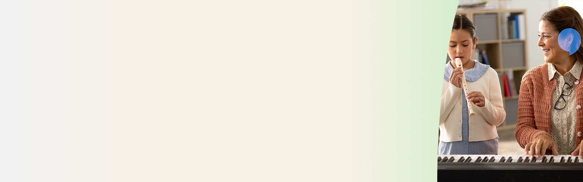 Una persona con apparecchio acustico suona una tastiera, mentre una bambina accanto tiene un flauto dolce; sullo sfondo c'è una libreria in un ambiente scolastico.