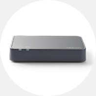 A sleek, rectangular Oticon hearing aid accessory, likely a TV adapter, rests on a neutral gray surface, designed to wirelessly stream audio to compatible hearing aids for enhanced sound quality.