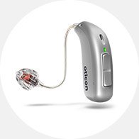 Een compacte zilvergrijze Oticon-hoortoestel met een discreet luidspreker-in-het-oor ontwerp, voorzien van een groen LED-lampje, weergegeven tegen een witte achtergrond voor gehoorzorgpromotie.