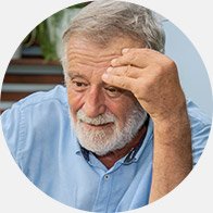 Older man in a blue shirt straining to hear in a conversation.