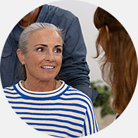 Une personne portant un haut rayé discute avec une audiologiste dans un cadre lumineux et accueillant, probablement une clinique Audika spécialisée dans les aides auditives et les tests d’audition.