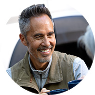 Man smiling while holding a coffee cup outdoors.