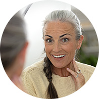 Profil d'une femme aux cheveux gris tressés portant un pull beige.