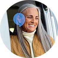 Una persona con cabello canoso lleva puesto un audífono Audika discreto en el oído derecho mientras está cerca de una puerta.